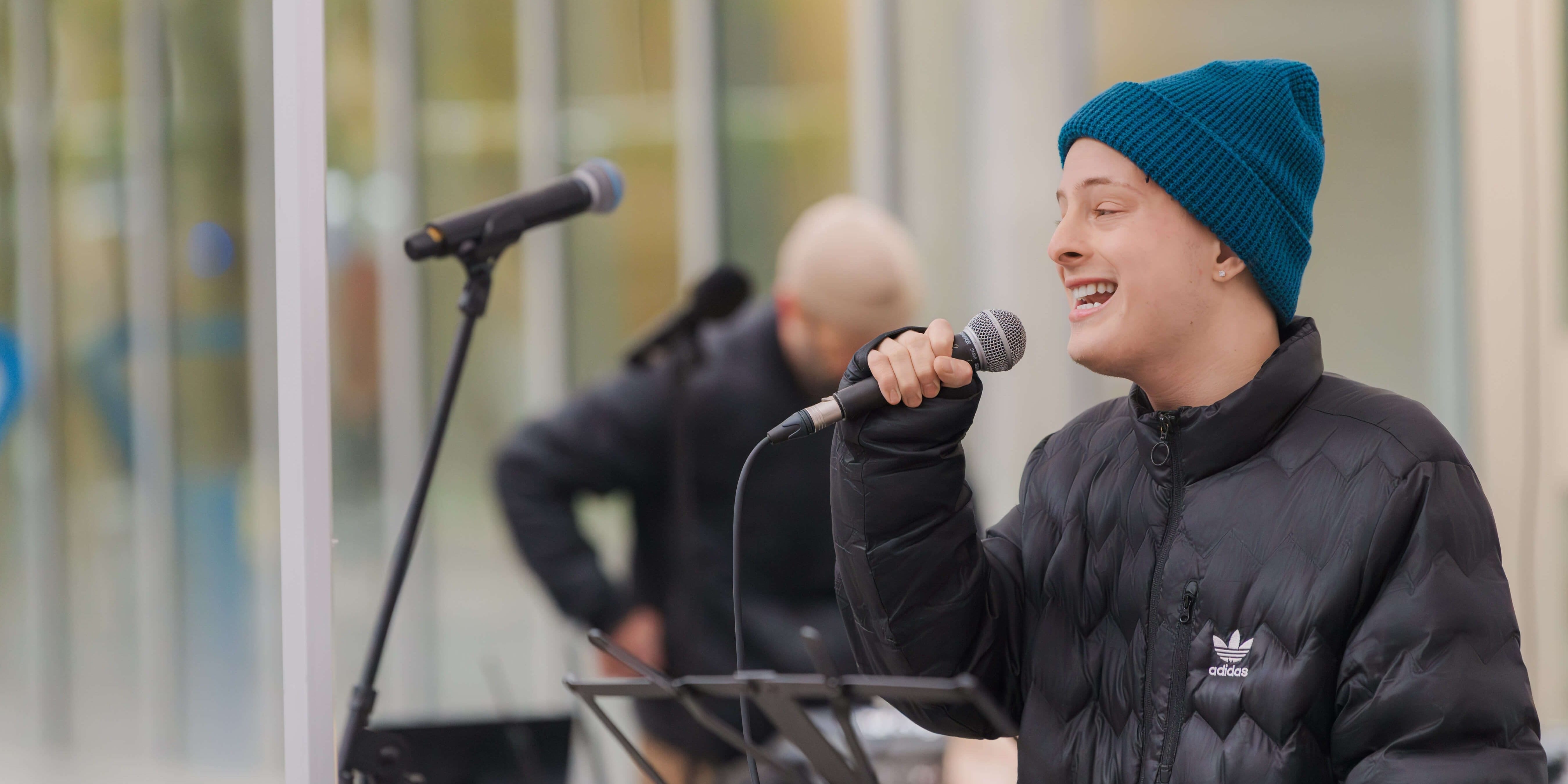 A student singing into a microphone at the TMU Frost Holiday Market.